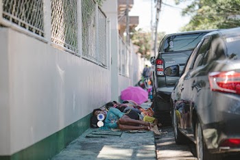 People Lying on Pavement Beside Parked Vehicles