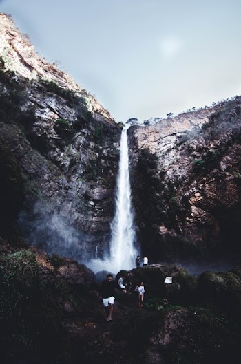 People on Brown Rock Near Waterfall