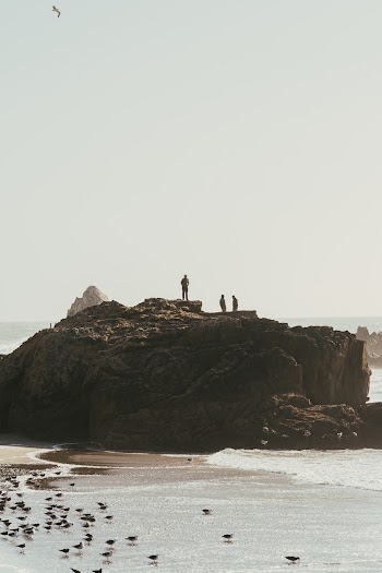 People on Rock Formation By The Sea Shore