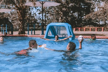 People on Swimming Pool Playing Ball