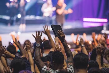 people raising hands in front of man performing on stage
