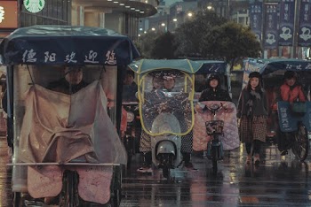 People Riding Bicycle or Motorcycle and Walking during Rain