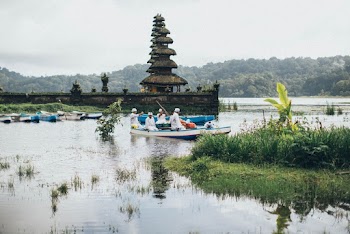 People Riding on Boat Near Brown Concrete Building