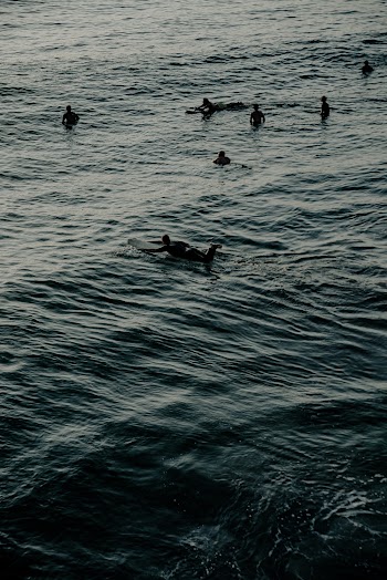 People Riding on Surfboard Near People Watching
