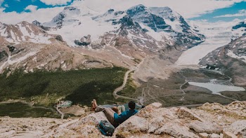 People Sitting By The Cliff Near Mountain Alps
