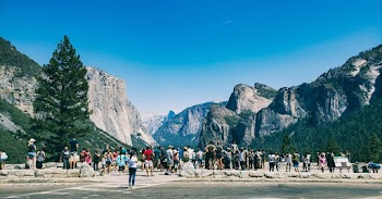 People Standing Across the Mountains Under Blue Sky