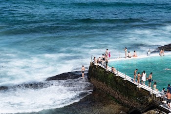 People Standing and Sitting on Beach Dock and Seashore Viewing Calm Sea