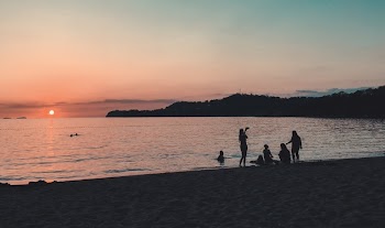 People Standing and Sitting on Seashore