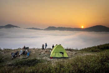 People Standing Near Camping Tent Overlooking Sea of Clouds during Golden Hour