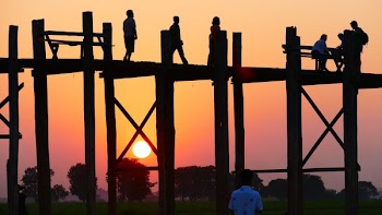 People Standing on a Bridge during Sunset .