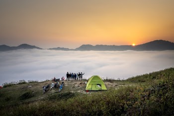 People Standing on Cliff Looking at Sea of Clouds