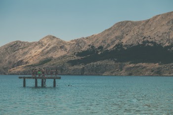 People Standing on Terrace in Middle of Body of Water Within Mountain Range