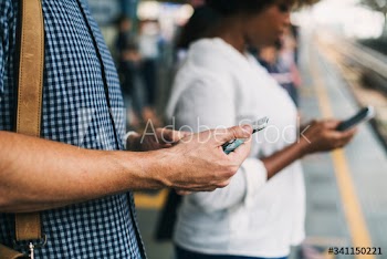 People using smartphones on a train platform