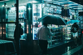 People Walking Along Sidewalk of a Store