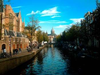 People Walking Beside River Under White Cloudy Sky