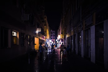 People Walking Between Buildings at Night