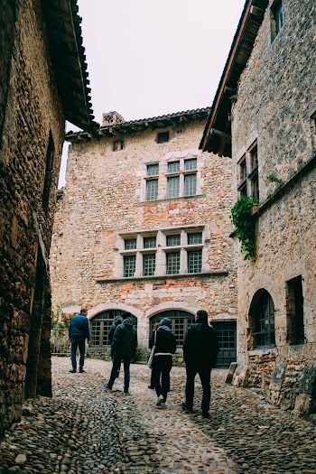People Walking in Between Stone Walled Buildings Along A Narrow Cobblestone Alley