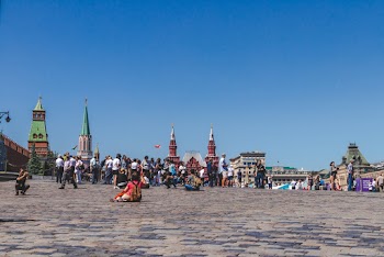 People Walking On A City Square Under Clear Blue Sky