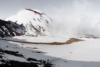 people walking on field near snow covered hill during daytime