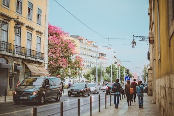 People Walking on Side Walk Between Road and Buildings
