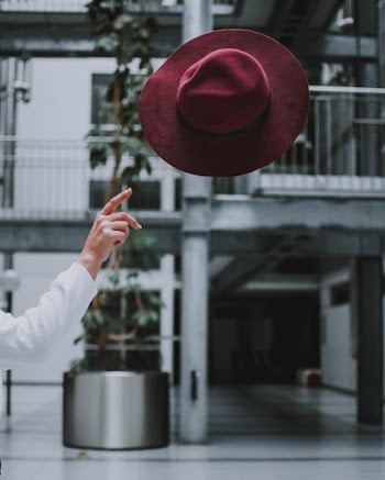 Person's Hand About to Throw Red Fedora Hat