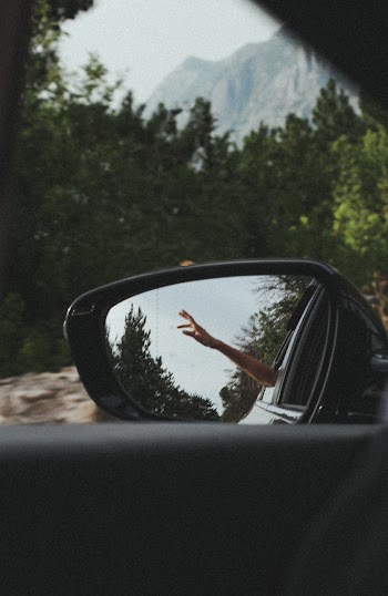Person's Hand Reflecting on Car Wing Mirror