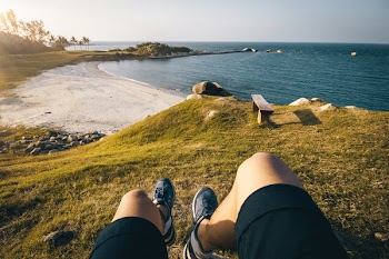 Person's Perspective on Grass Field and Body of Water