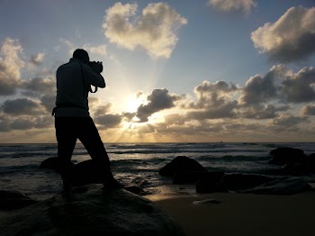 Person Capturing Photo Near Sea Under Clear Blue and White Cloudy Sky during Daytime