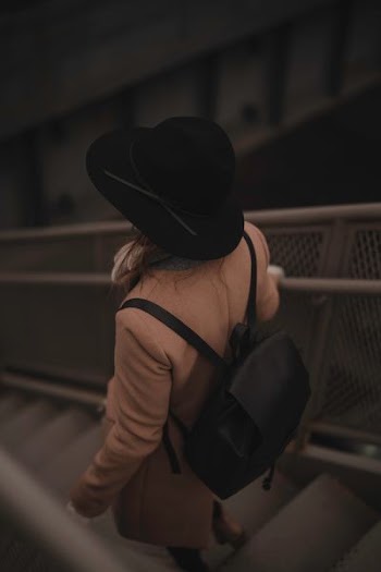 person carrying black backpack while walking downards of stair
