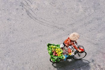 person carrying black bike with basket of fruits