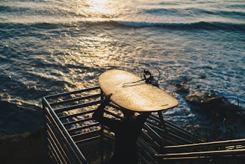 Person Carrying Brown Surfboard Near Body of Water during Golden Hour