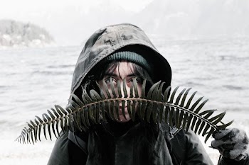 person covering her face with green fern