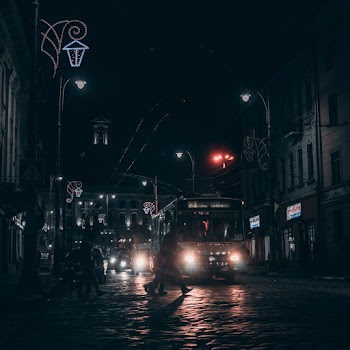 Person Crossing The Street Near Bus during Night Time