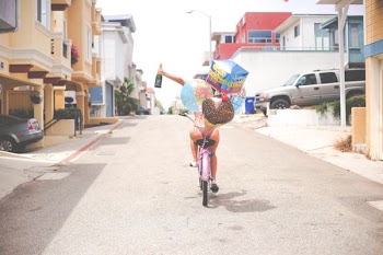 person cycling on street while raising a bottle of liquor
