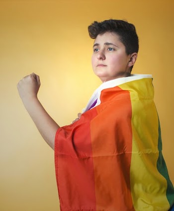 Person Draped In Pride Flag Gazing Into A Bright Future