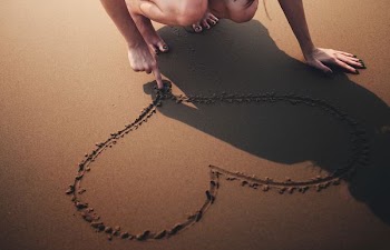 person draw heart shape on seashore