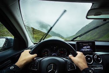person driving Mercedes-Benz car during daytime