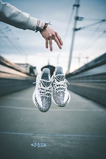person dropped sneakers on gray sidewalk during daytime