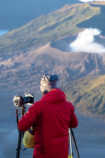 Person Fixes Camera on Top of the Mountain