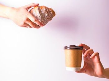 Person Hand Holding Disposable Cup and Croissant
