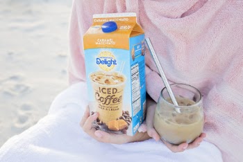 Person Holding a Carton and glass filled with Delight Iced Coffee