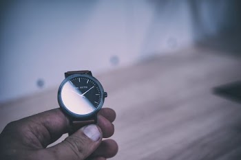 person holding analog watch displaying 10:10