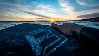 Person Holding Black and Gray Board Facing Blue Sea Under Blue Sky