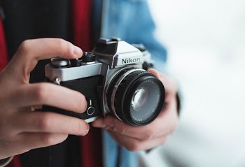 person holding black and gray Nikon DSLR camera