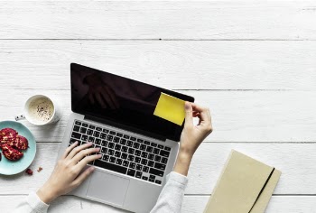Person Holding Black And Grey Laptop Computer On Top Of White Wood Surface