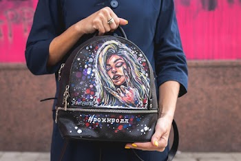 Person Holding Black and Multicolored Leather Backpack