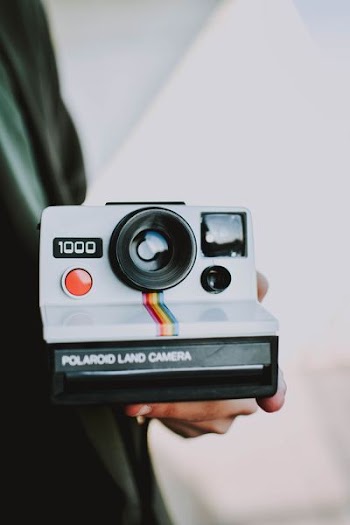 person holding black and white Polaroid land camera