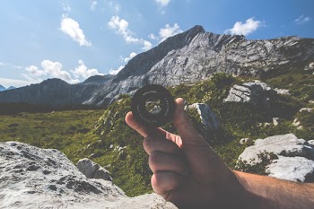 Person Holding Black Camera Lens Near Mountain
