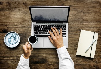 Person Holding Black Ceramic Cup and Macbook Pro