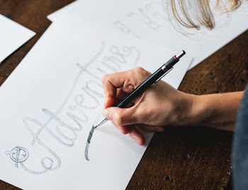 person holding black click pen while writing